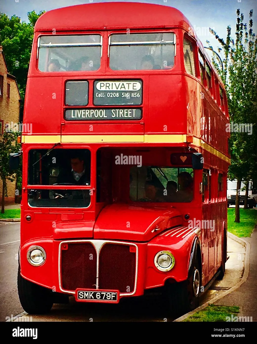 A bright red double decker bus converted into a coffee shop parked in a sunny courtyard
